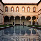 Cortile del Castello Sforzesco con piscina riflettente e portico ad archi.