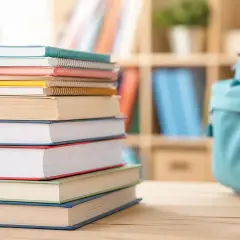 Pila di libri colorati, zaino azzurro e astuccio con matite. Un'immagine che evoca la voglia di studiare e la possibilità di un bonus libri ISEE.