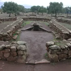 Antichi pozzi sacri in Sardegna, con mura in pietra a secco e una scala che scende nell'acqua.