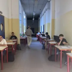 Studenti seduti ai banchi in un'aula scolastica, concentrati sull'esame di quinta elementare. Un insegnante cammina tra i banchi.
