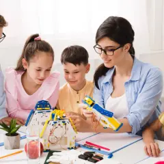 Bambini e insegnante costruiscono robot, un'attività che illustra il significato di itp scuola: apprendimento pratico e innovazione.