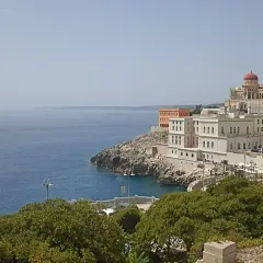 Vista sul mare e sul complesso dell'istituto alberghiero Santa Cesarea Terme, con edifici bianchi e una cupola rossa.