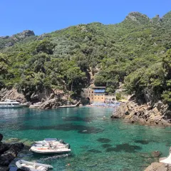 Baia di San Fruttuoso con acque cristalline, barche e persone che nuotano. Un luogo ideale per il trekking e il relax.