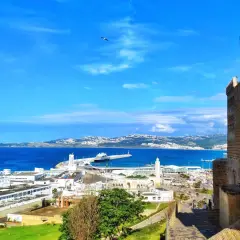 Vista panoramica di Tangeri: il porto, il mare blu e un'antica fortezza. Un luogo ricco di storia e cose da vedere.