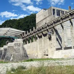 Imponente struttura industriale abbandonata nel parco delle gole della Breggia, con passerelle e finestre che si stagliano contro il cielo azzurro.