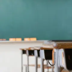 Banchi vuoti in aula, con lavagna verde sullo sfondo. Chissà quanto guadagna un professore delle medie per insegnare qui.