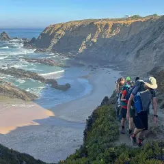 Escursionisti sul sentiero dei pescatori in Portogallo, con scogliere rocciose e oceano Atlantico.