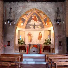 Interno di una chiesa con affreschi antichi e panche di legno. L'altare presenta un dipinto di San Cristoforo, simbolo di protezione per i viaggiatori a San Cristoforo, Milano.