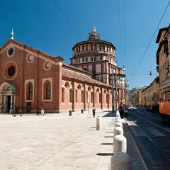 Piazza antistante Santa Maria delle Grazie con tram arancione in transito.