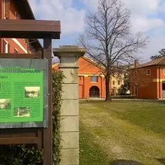 Cartello informativo sui cenni storici di Fossalta di Portogruaro, con edifici storici sullo sfondo.