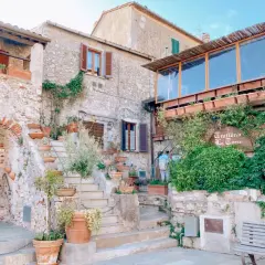 Un angolo incantevole tra i borghi vicino Capalbio, con scale di pietra, vasi di terracotta e la trattoria "La Torre" avvolta dal verde.