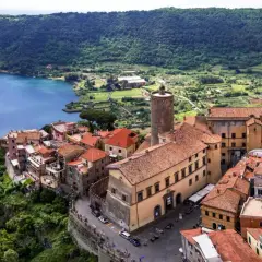 Nemi, un gioiello sui Castelli Romani, si affaccia sul lago. Case con tetti rossi si aggrappano alla collina, con una torre medievale che domina il panorama.