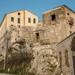 Antiche mura e un edificio giallo a Montesarchio, Benevento, si stagliano contro il cielo azzurro.