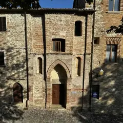 Antica facciata in pietra e mattoni a Macerata Feltria, con un portale ad arco e finestre storiche.