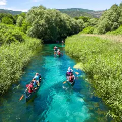 Persone in canoa su un fiume cristallino, un'ottima idea per visitare l'Abruzzo con itinerari naturalistici.