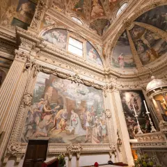 Interior of a church with ornate frescoes depicting religious scenes on walls and ceiling.