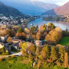 Un antico borgo si affaccia sul lago di Endine, circondato da colline verdi e montagne.