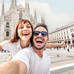 Coppia felice scatta un selfie a Milano, con il Duomo sullo sfondo. Perfetto per chi cerca visite guidate gratuite a Milano!