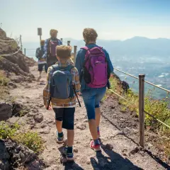 Famiglia in escursione sul sentiero del **Parco Nazionale del Vesuvio**, con vista panoramica sulla costa.