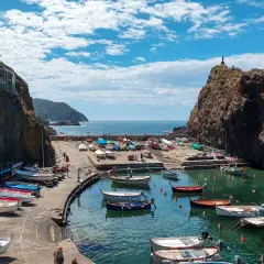 Un pittoresco porticciolo a **Framura, Liguria**, con barche colorate sull'acqua cristallina e scogliere a picco.
