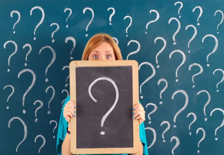 Ragazza con lavagna piena di punti interrogativi, come per le prove invalsi che sono obbligatorie.
