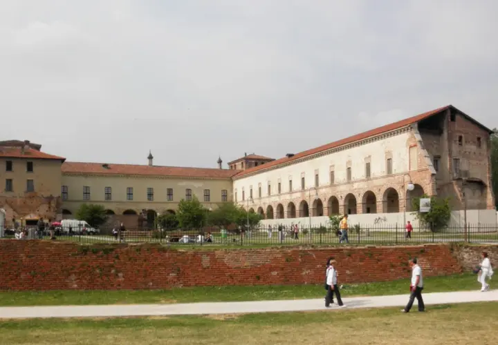 Il castello di Melegnano, con la sua architettura storica, accoglie visitatori e passeggiatori in una giornata nuvolosa.