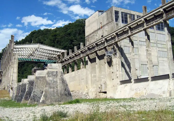 Imponente struttura industriale abbandonata nel parco delle gole della Breggia, con passerelle e finestre che si stagliano contro il cielo azzurro.