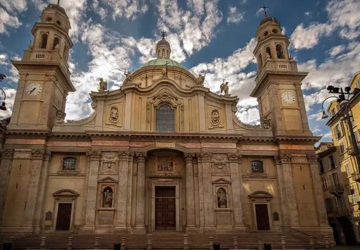 La maestosa facciata della chiesa Sant'Alessandro a Milano, con le sue torri campanarie e la cupola, si staglia contro un cielo azzurro e nuvoloso.