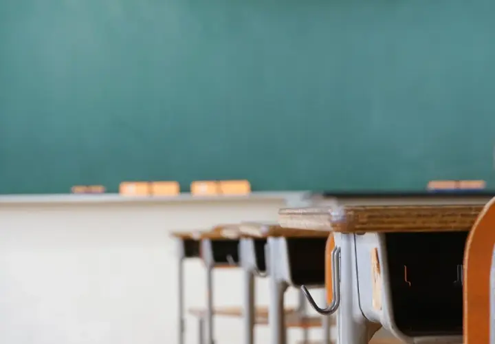 Banchi vuoti in aula, con lavagna verde sullo sfondo. Chissà quanto guadagna un professore delle medie per insegnare qui.
