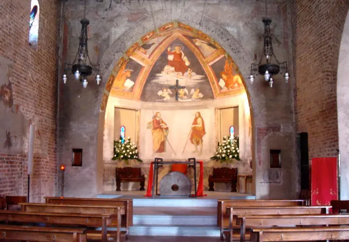 Interno di una chiesa con affreschi antichi e panche di legno. L'altare presenta un dipinto di San Cristoforo, simbolo di protezione per i viaggiatori a San Cristoforo, Milano.