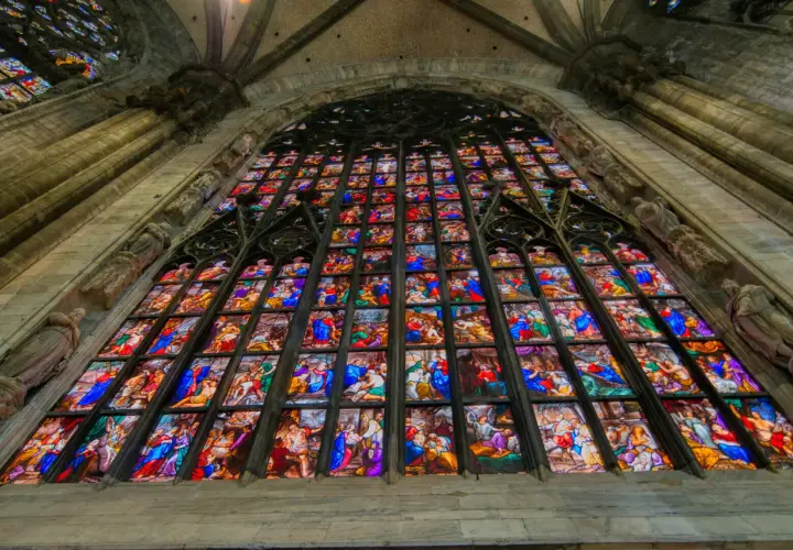 Le vetrate del Duomo di Milano narrano storie sacre con colori vibranti, un capolavoro di arte gotica che illumina l'interno.