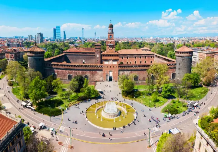 Il castello di Milano, imponente e storico, si erge maestoso con le sue torri e il cortile animato da visitatori.