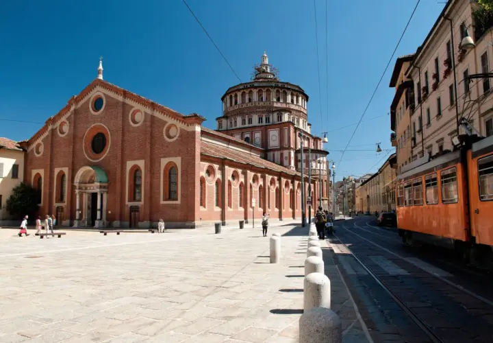 Piazza antistante Santa Maria delle Grazie con tram arancione in transito.
