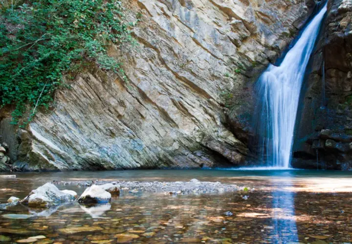 Cascate in Basilicata: acqua cristallina scende da rocce stratificate, circondate da vegetazione lussureggiante. Un angolo di paradiso naturale.