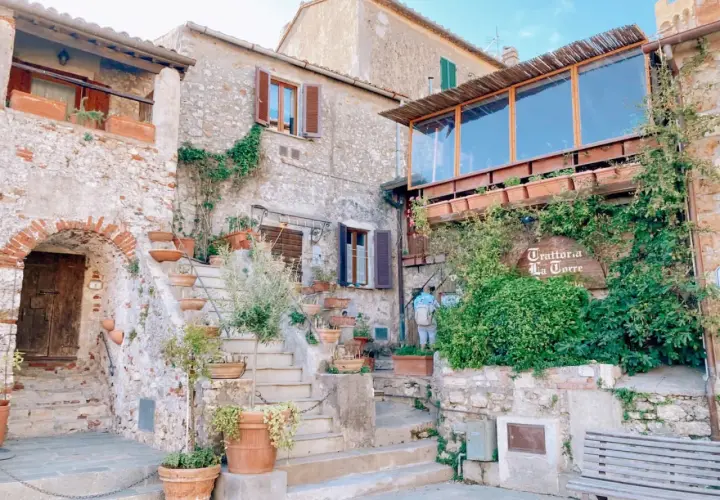 Un angolo incantevole tra i borghi vicino Capalbio, con scale di pietra, vasi di terracotta e la trattoria "La Torre" avvolta dal verde.