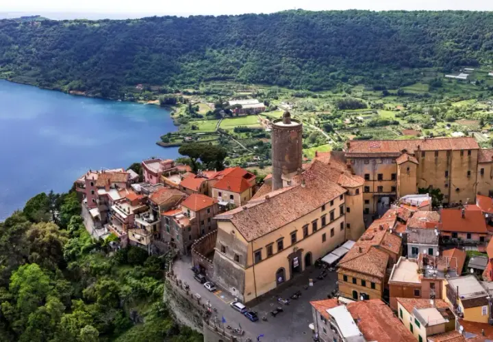 Nemi, un gioiello sui Castelli Romani, si affaccia sul lago. Case con tetti rossi si aggrappano alla collina, con una torre medievale che domina il panorama.