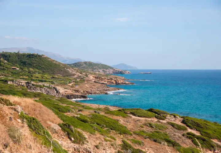 Costa selvaggia tra Alghero e Bosa, con macchia mediterranea, rocce dorate e mare turchese.