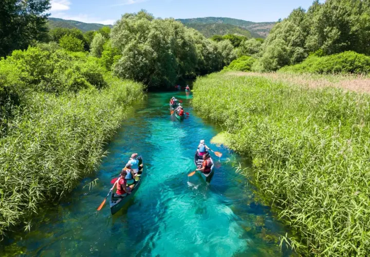 Persone in canoa su un fiume cristallino, un'ottima idea per visitare l'Abruzzo con itinerari naturalistici.