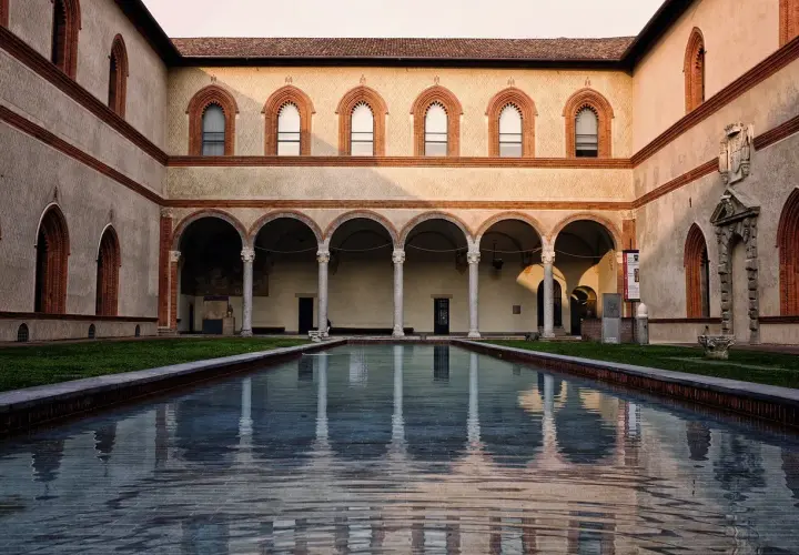 Cortile del Castello Sforzesco con piscina riflettente e portico ad archi.