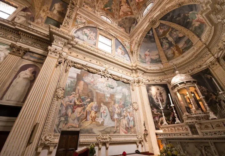 Interior of a church with ornate frescoes depicting religious scenes on walls and ceiling.