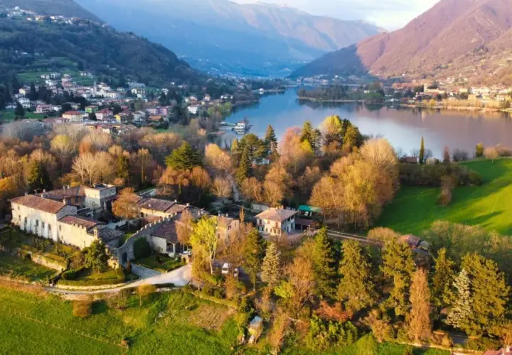 Un antico borgo si affaccia sul lago di Endine, circondato da colline verdi e montagne.