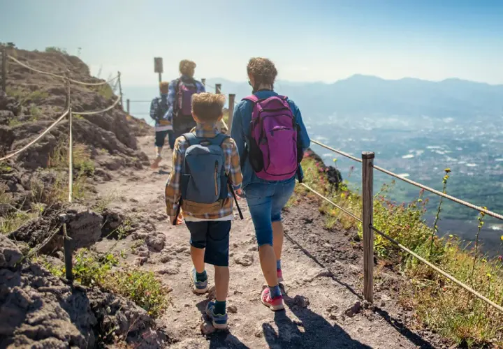 Famiglia in escursione sul sentiero del **Parco Nazionale del Vesuvio**, con vista panoramica sulla costa.