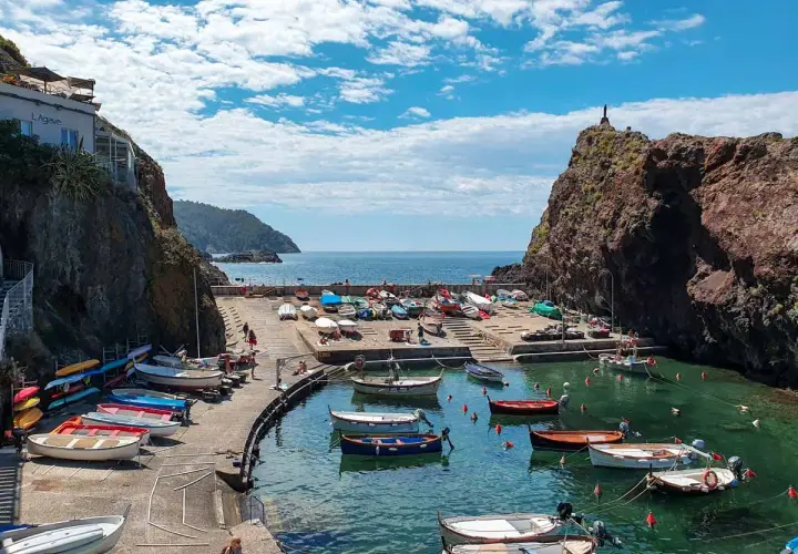 Un pittoresco porticciolo a **Framura, Liguria**, con barche colorate sull'acqua cristallina e scogliere a picco.