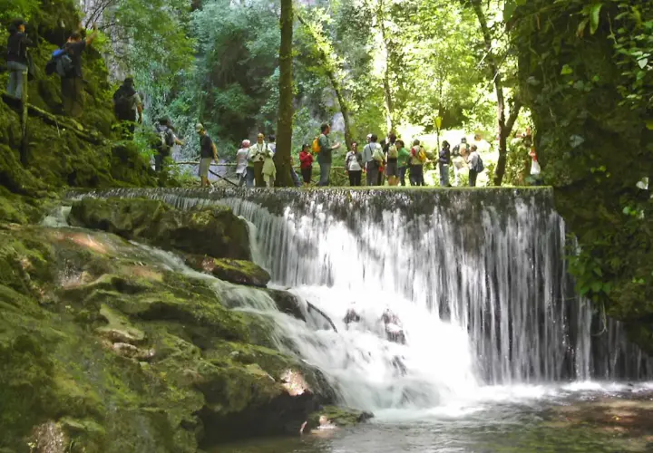 Cascata nella Valle delle Ferriere ad Amalfi, con un gruppo di escursionisti che osserva il panorama.