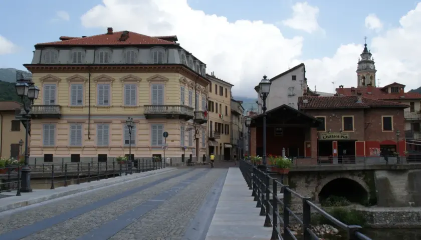 Ponte acciottolato a Garessio, con edifici storici e la torre dell'orologio che svetta. L'altitudine di Garessio offre scorci suggestivi.