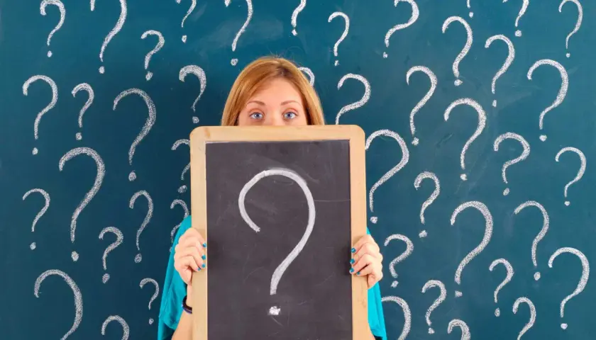 Ragazza con lavagna piena di punti interrogativi, come per le prove invalsi che sono obbligatorie.