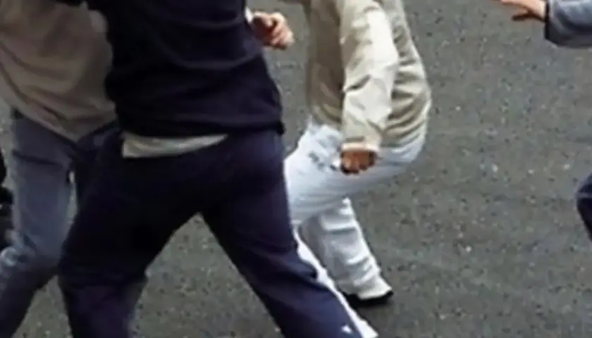 Un gruppo di ragazzi è coinvolto in una rissa a scuola. Si vedono pugni e corpi in movimento.