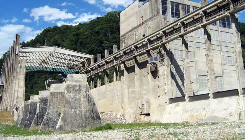 Imponente struttura industriale abbandonata nel parco delle gole della Breggia, con passerelle e finestre che si stagliano contro il cielo azzurro.