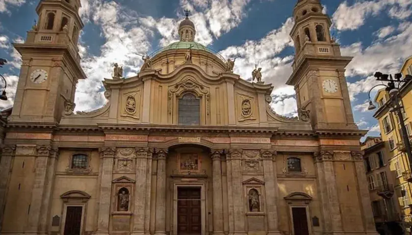 La maestosa facciata della chiesa Sant'Alessandro a Milano, con le sue torri campanarie e la cupola, si staglia contro un cielo azzurro e nuvoloso.