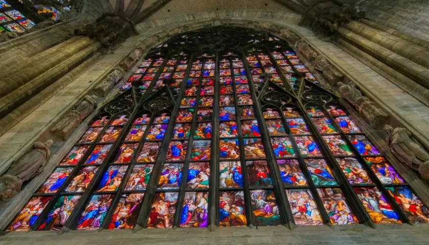 Le vetrate del Duomo di Milano narrano storie sacre con colori vibranti, un capolavoro di arte gotica che illumina l'interno.